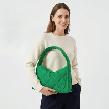 Model wearing a forest green quilted puffy hobo bag for an urban chic look.