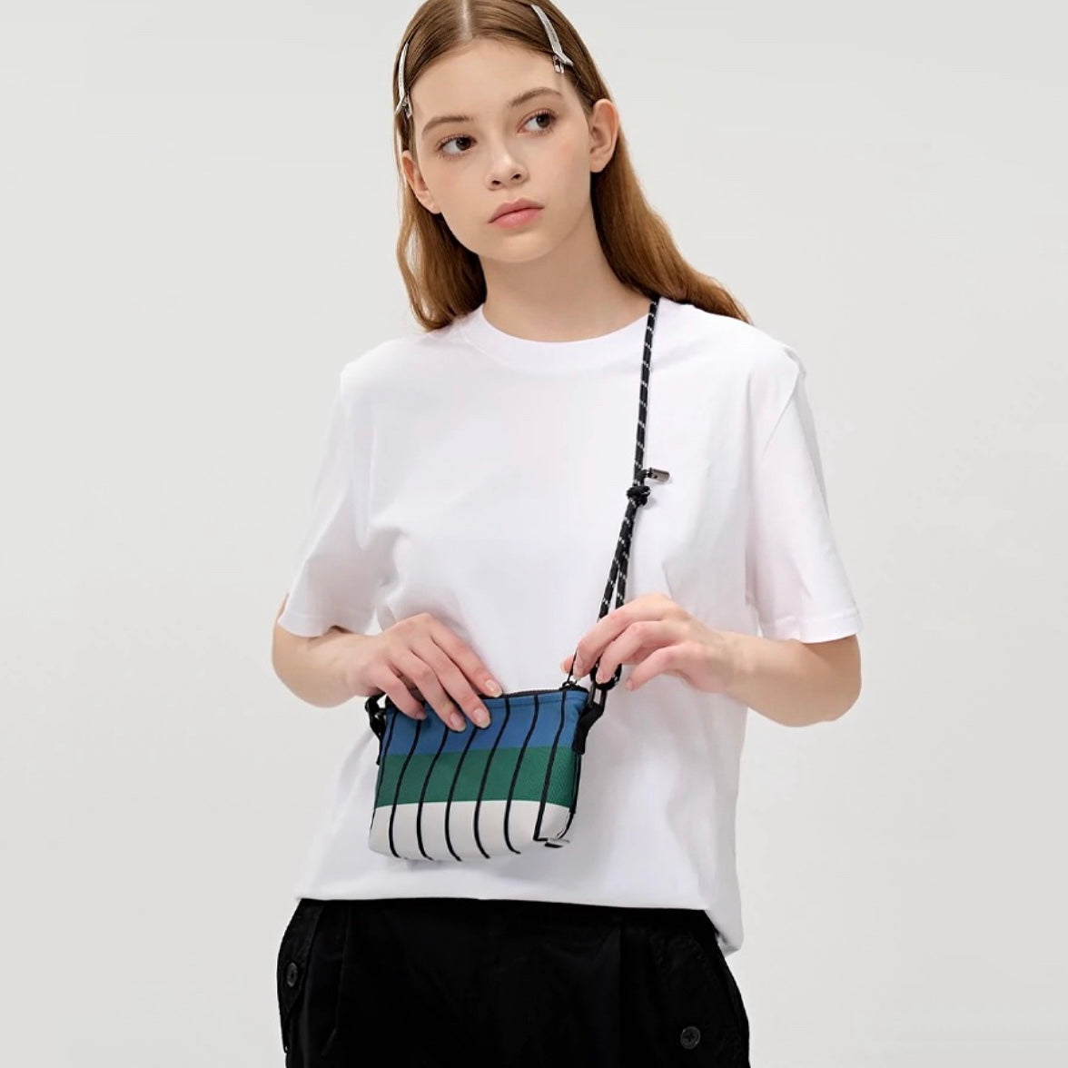 Model showcasing the compact size of the striped Oxford bag, ideal for lightweight travel.