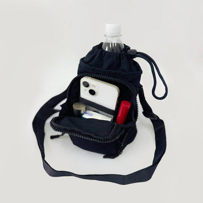 Close-up of the functional drawstring closure and front zip pocket of a technical fabric bottle bag.
