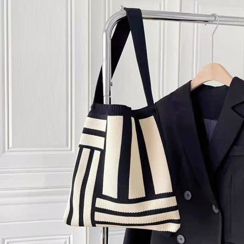 Front view of black Geometric Line Knitted Bag hanging on a hanger , great for everyday carry and travel.