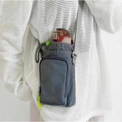 A model wearing a grey crossbody bottle bag, showcasing its compact and lightweight urban utility style.