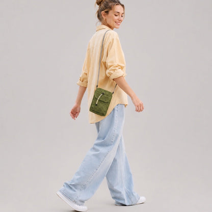 Side view of a model carrying the lightweight green ripstop utility crossbody bag on her shoulder.