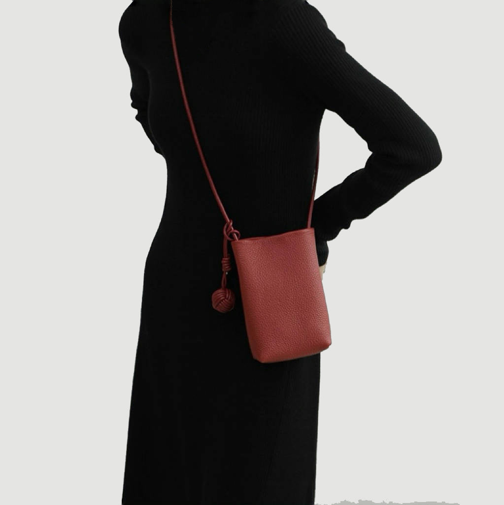 Model carrying a red  hanging ball leather crossbody bag, easy for commuting and weekends.