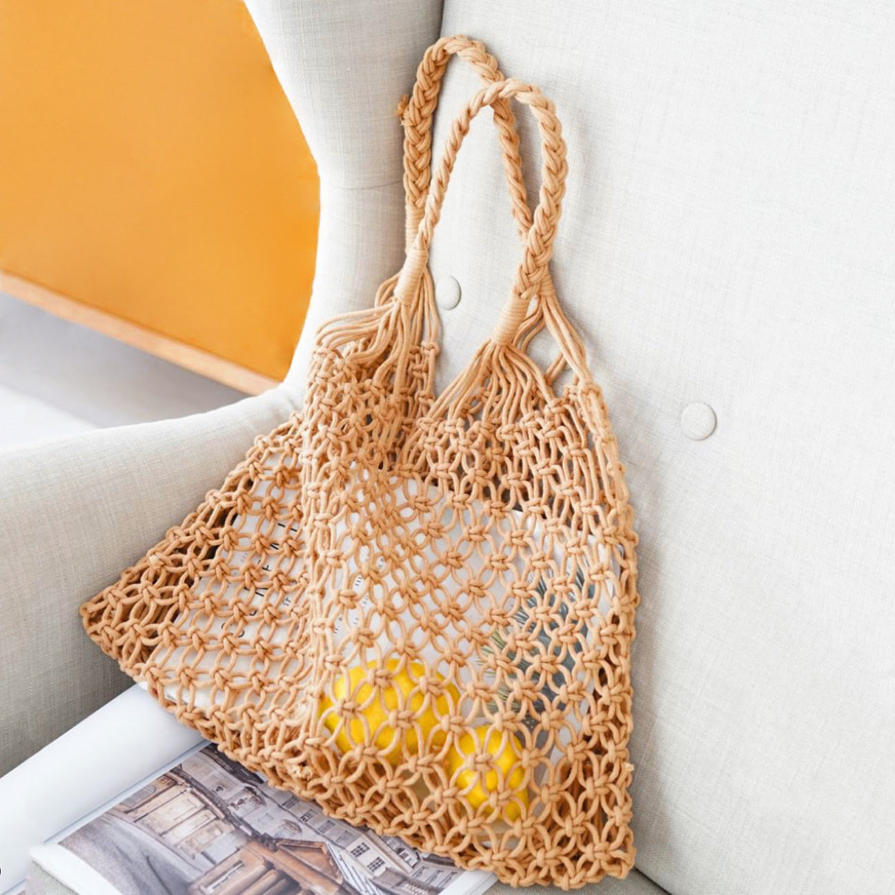 Close-up of Tan hollow crochet tote bag made from cotton rope with braided handles in camel.