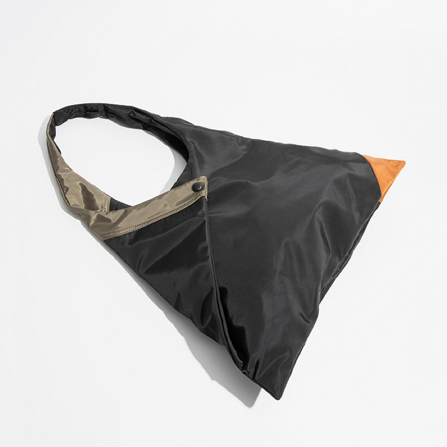 Flat lay of the geometric triangle tote bag highlighting the foldable design and orange corner accent.