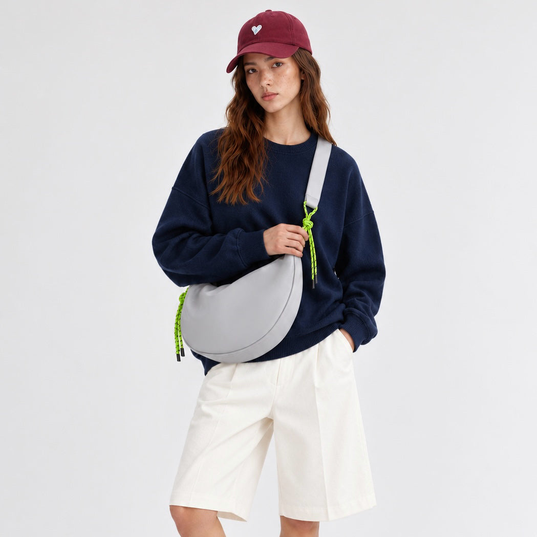 Model styling a grey knotted nylon sling bag, minimalist everyday cool accessory for urban nomads.
