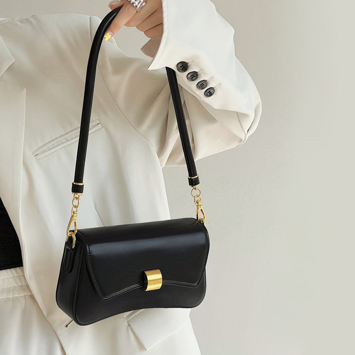 Model carrying a black Light Leather Arc Baguette Shoulder Bag handheld, great for daily carry and travel.