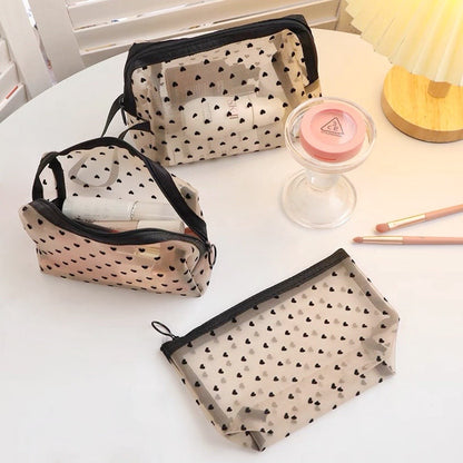 Three heart print organza bags with various shapes on a vanity table, trapezoidal, rectangle and handle.