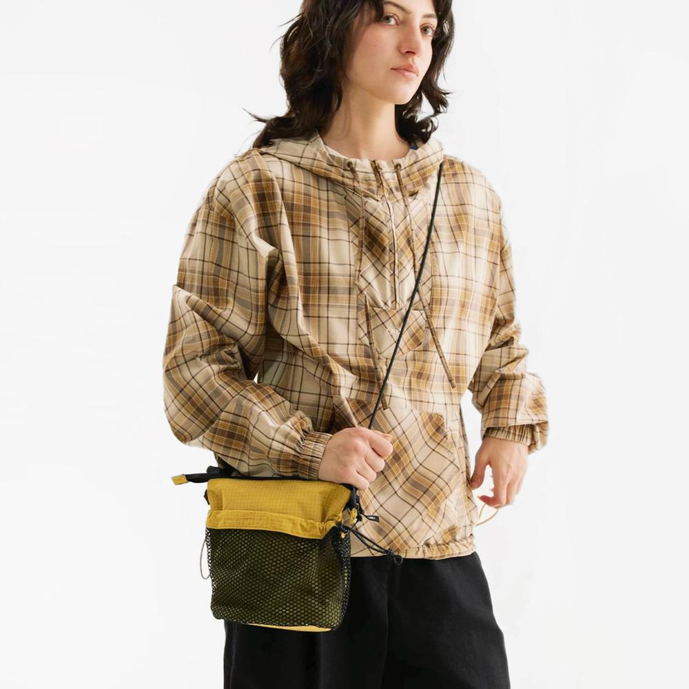 Model carrying a khaki nylon crossbody bag handheld, ideal for city walks and gifting.