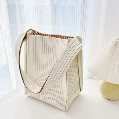 Close-up of Cream woven tote bag with vertical texture, milk carton design, and brown striped lining.