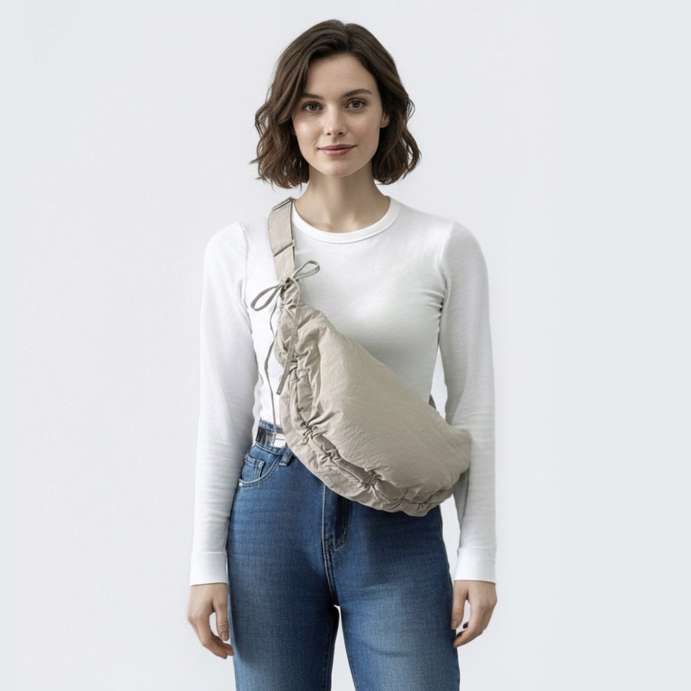 Model carrying a khaki crescent bag as a crossbody for a minimalist urban aesthetic.