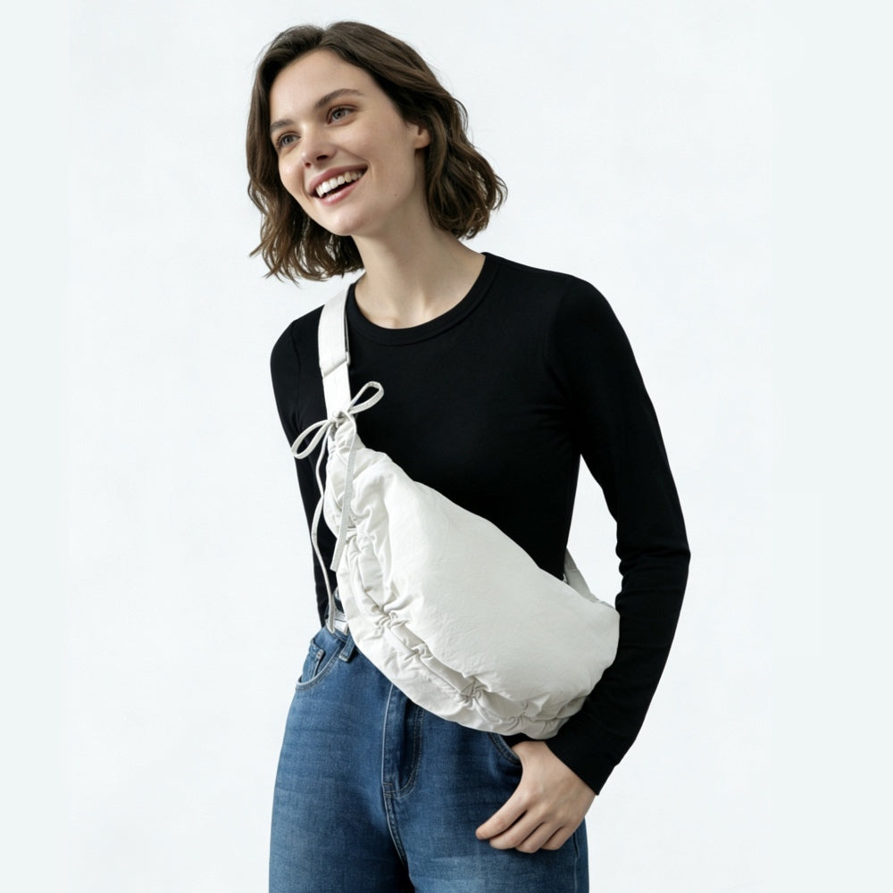 Model carrying the white duvet crescent bag as a crossbody for a minimalist urban style.