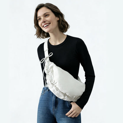 Model carrying the white duvet crescent bag as a crossbody for a minimalist urban style.