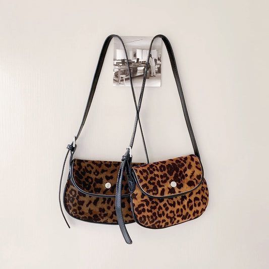 Two mini leopard print vegan suede saddle bags with black straps and magnetic flap closures. great for everyday carry.