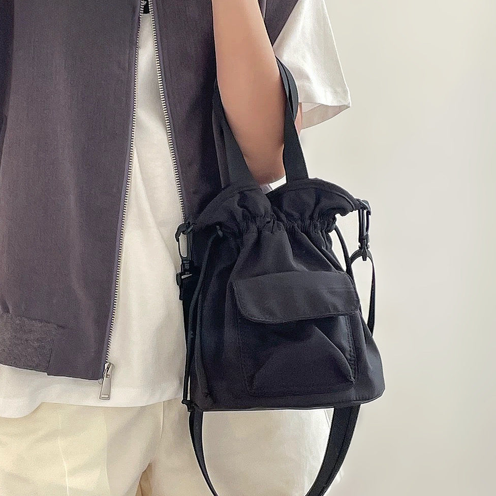 Sleek black mini nylon bucket bag styled for an urban streetwear look.
