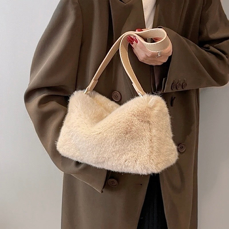 Model carrying a beige mini fluffy shearling baguette bag handheld, great for daily carry and travel.