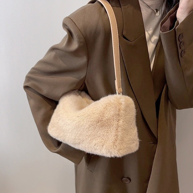 Model carrying a beige mini fluffy shearling baguette bag on the shoulder, easy for commuting and weekends.