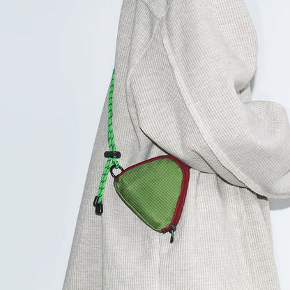 A model wearing a green triangle mini bag as a crossbody, highlighting the geometric style impact.