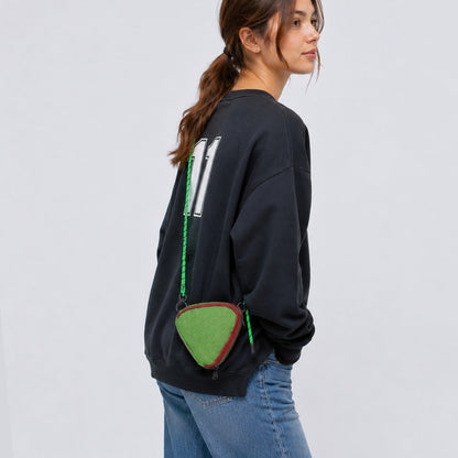 A model wearing a green triangle mini bag as a crossbody, highlighting the geometric style impact.