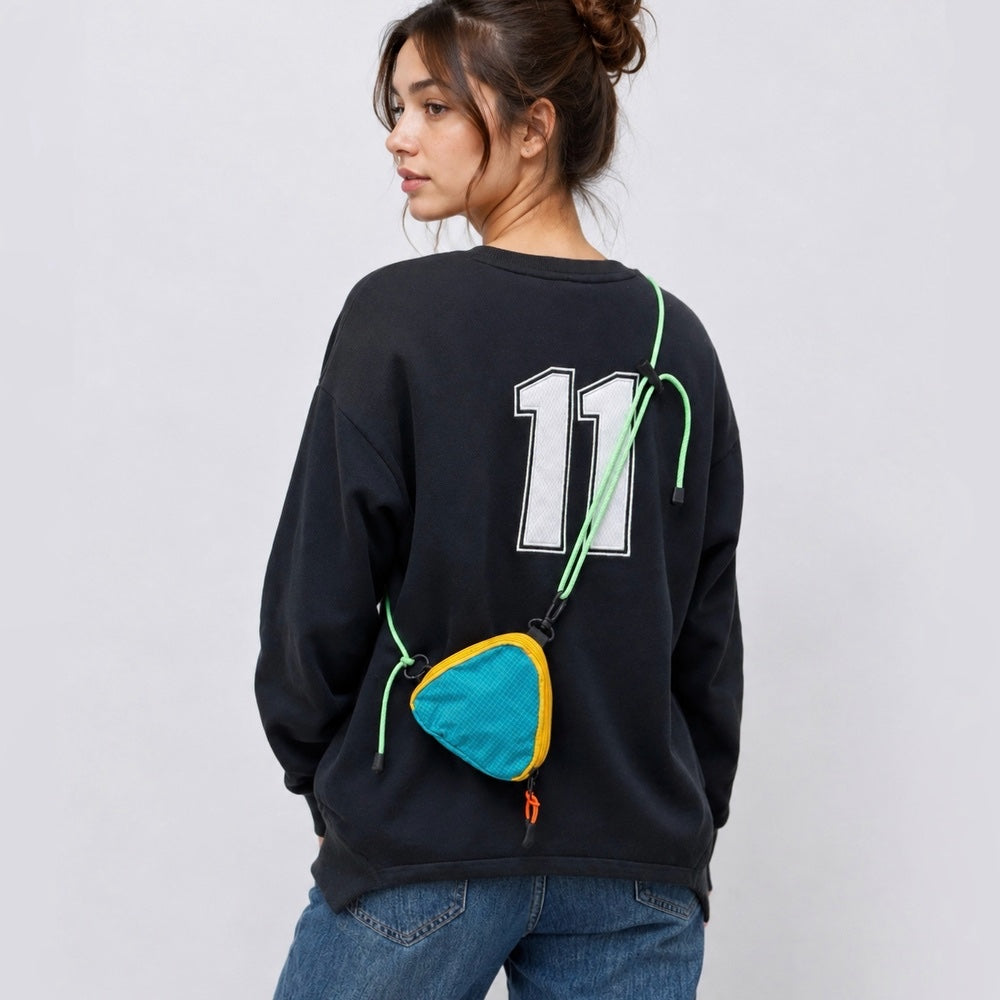 A model wearing a blue triangle mini bag as a crossbody, highlighting the geometric style impact and adjustable strap.