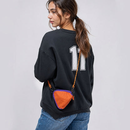 A model wearing an orange triangle mini bag as a crossbody, highlighting the geometric style impact.