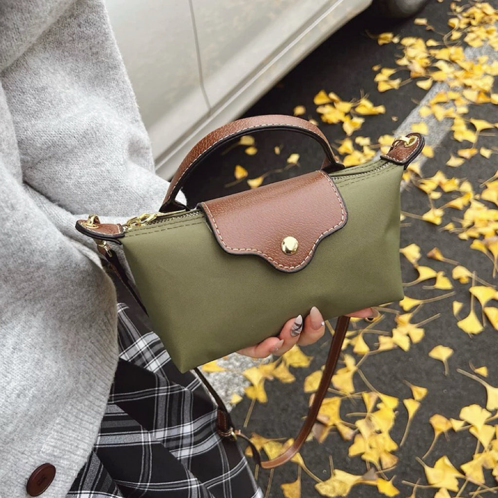 Olive green mini nylon dumpling bag featuring brown leather flap closure and handle.