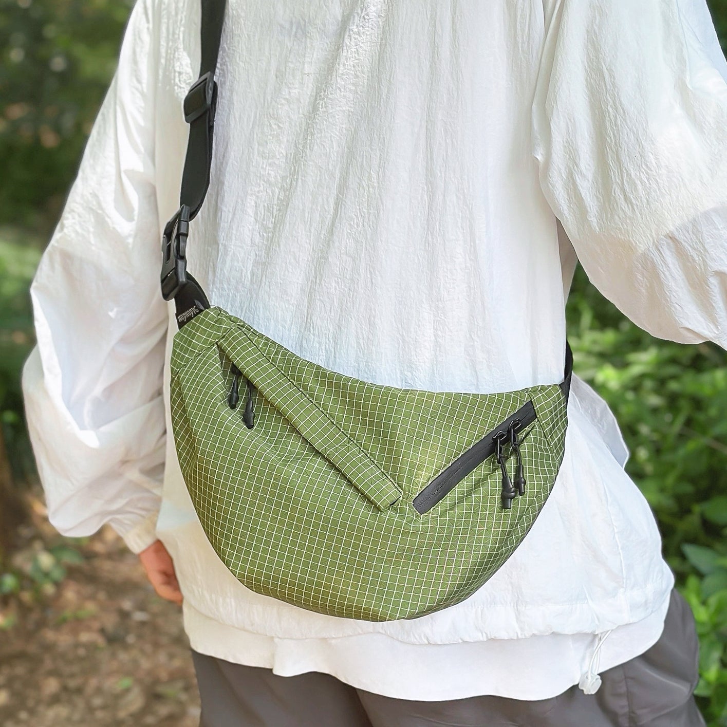 Model carrying a green plaid nylon sling bag as crossbody, easy for commuting and weekends.
