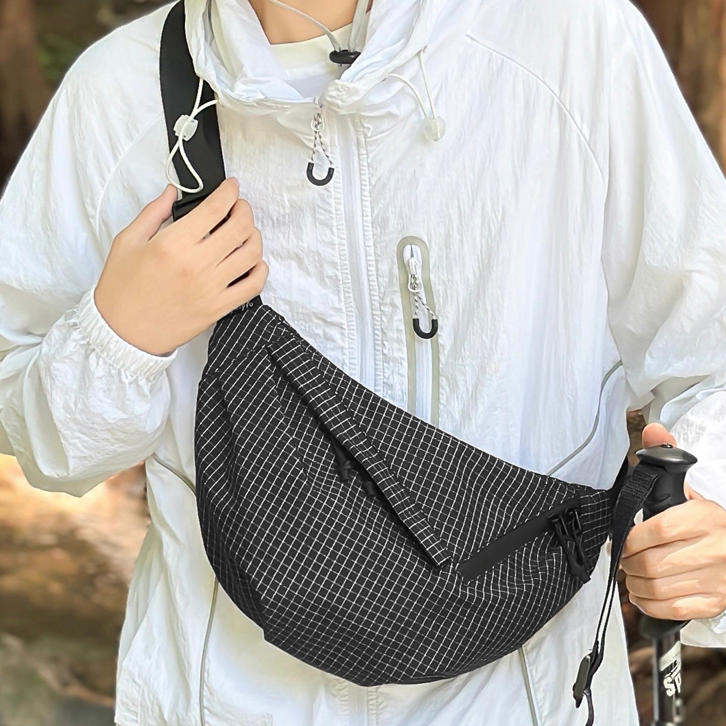 Model carrying a black plaid nylon sling bag as crossbody, ideal for city walks and gifting.