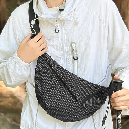 Model carrying a black plaid nylon sling bag as crossbody, ideal for city walks and gifting.