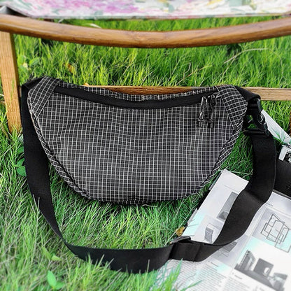 Flat lay of Plaid Venture Nylon Sling Bag in black, easy for commuting and weekends.