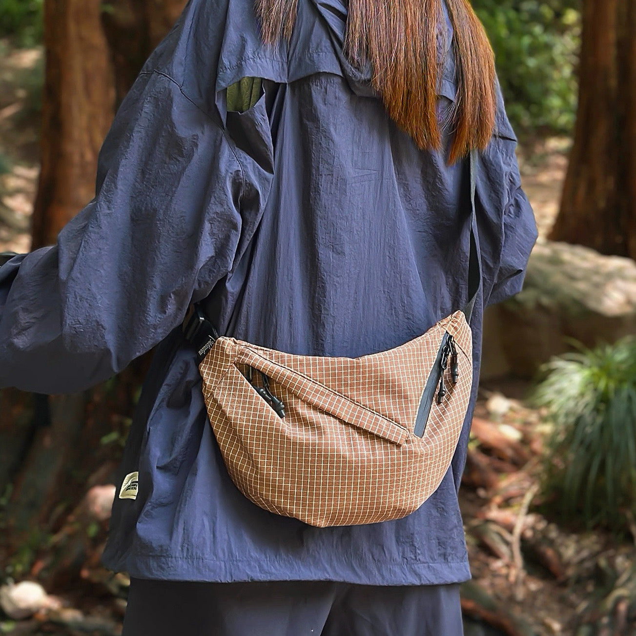 Model carrying a brown plaid nylon sling bag as crossbody, ideal for city walks and gifting.