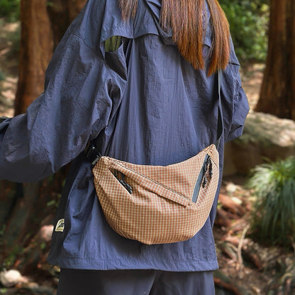 Model carrying a brown plaid nylon sling bag as crossbody, ideal for city walks and gifting.