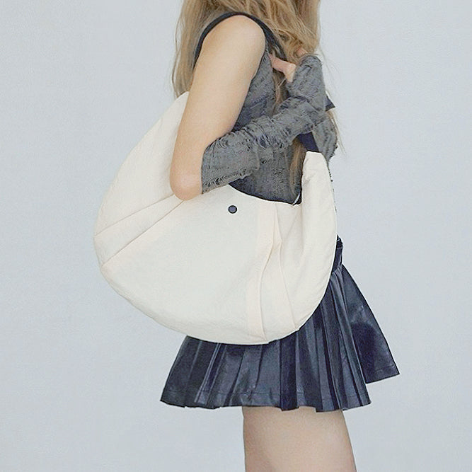 Model carrying a beige nylon shoulder bag , great for daily carry and travel.