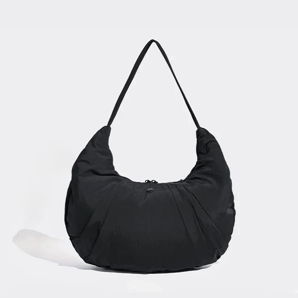 Angled view of Pleated Crescent Shoulder Bag in black, great for everyday carry and travel.