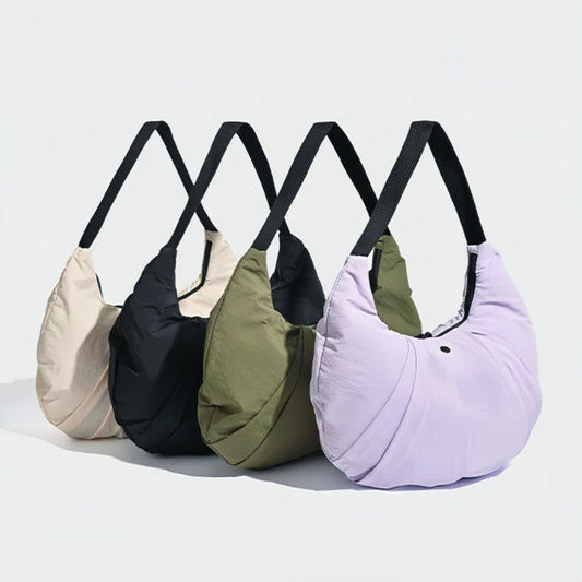 Four pleated nylon crescent shoulder bags in beige, black, olive, and light purple with black straps.