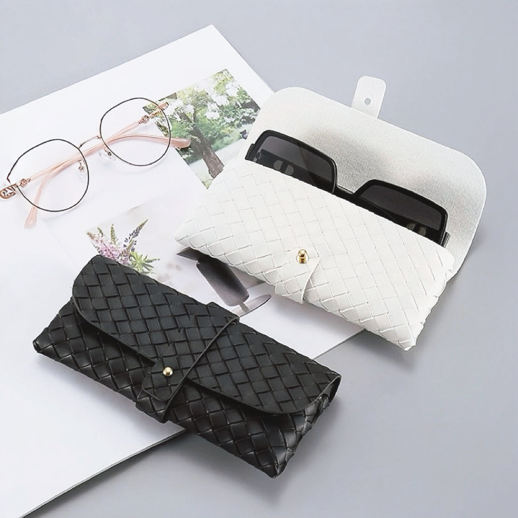 Angled view of two Portable Woven Leather Glasses Case show together, black is close and white is open.
