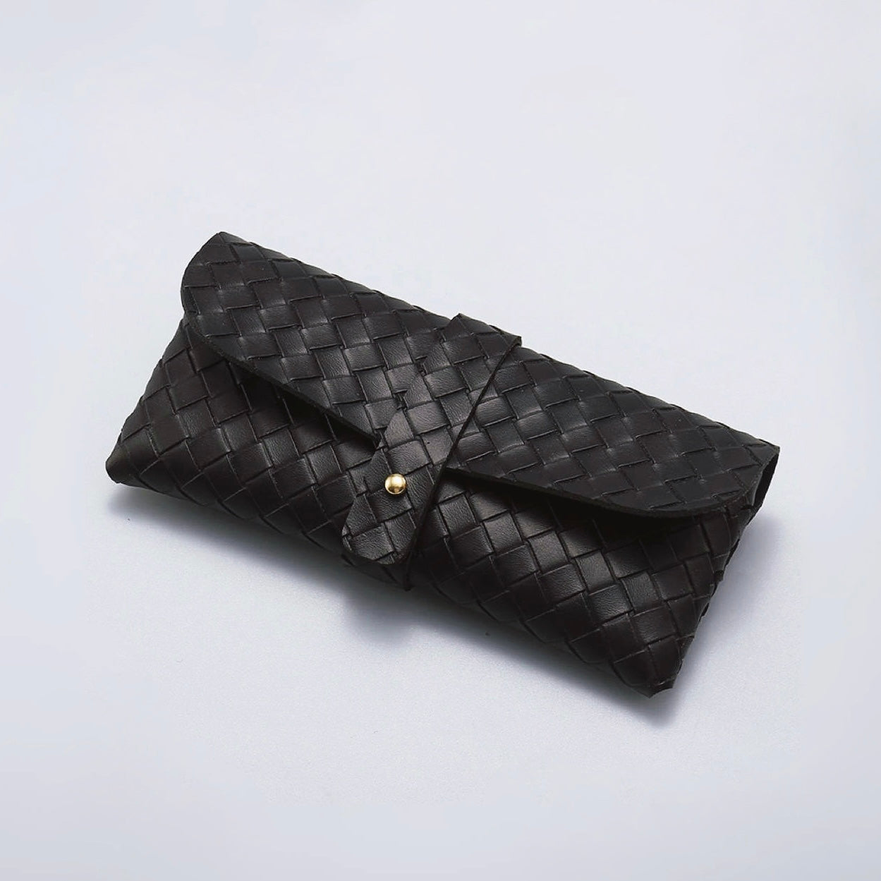 Flat lay of black Portable Woven Leather Glasses Case with buckle closure.