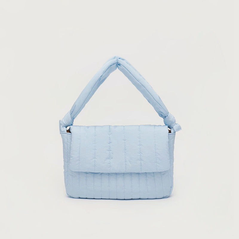 Front view of Light blue puffy quilted nylon bag with an adjustable knotted strap and magnetic flap closure.