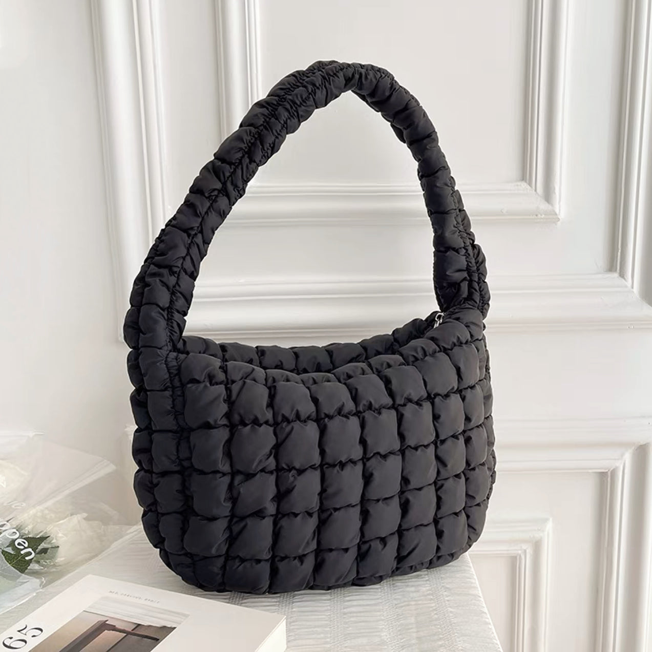 Front view of classic black puffy shoulder bag on a white background.