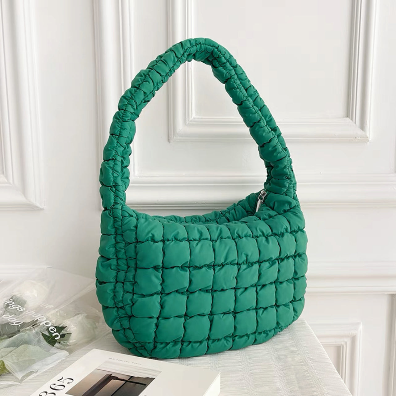 Close-up of the high-quality quilted stitching on the dark green puffy bag.