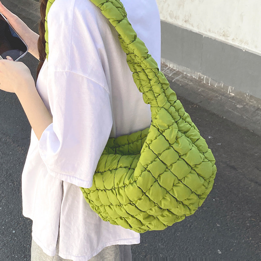Model wearing the light green puffy bag on her shoulder showcasing the soft silhouette.