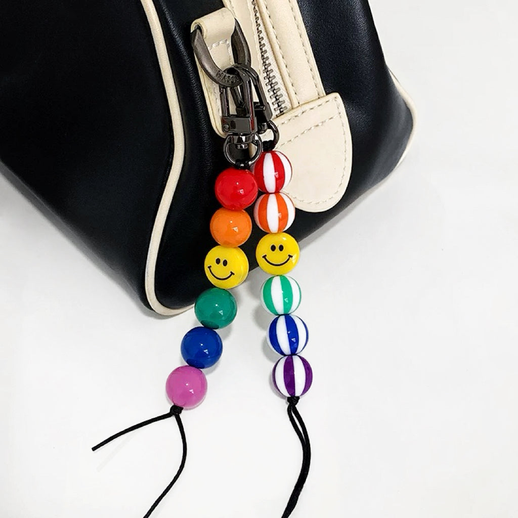 Two style of Rainbow Smile Bead Link Bag Charms hanging on a bag zipper, ideal for everyday outfits and street style.