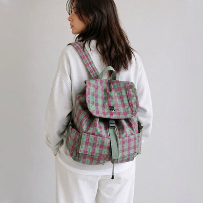 Back view of a model wearing the pink and green plaid laptop backpack flat against the lower back.