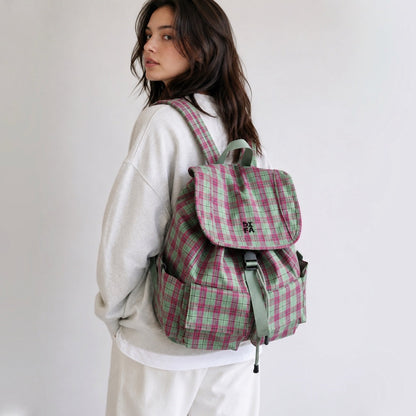 Side view of a model styling the pink and green plaid aesthetic school bag over one shoulder.