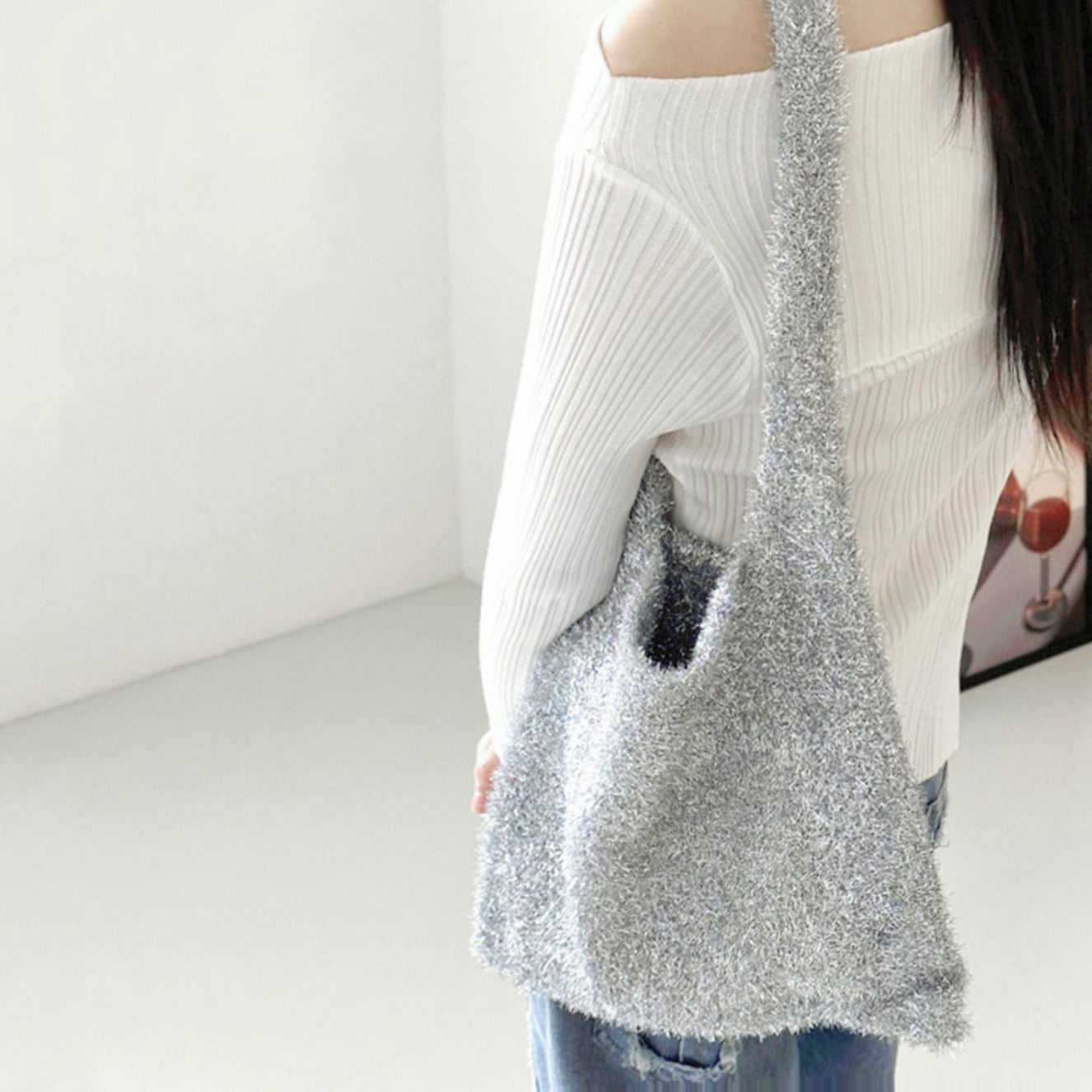 Silver sparkle knit bag showing off its soft, effortless drape on the shoulder.