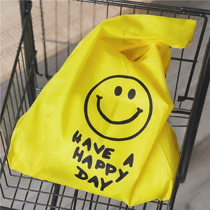 Bright yellow foldable shopper bag with black smiley face and HAVE A HAPPY DAY text.