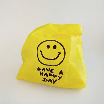 Bright yellow foldable shopper bag with a black smiley face and HAVE A HAPPY DAY text.