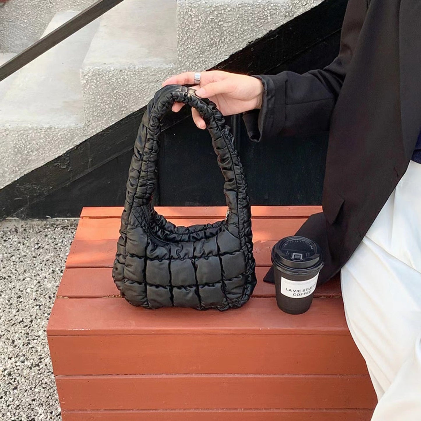 Model carrying a black Soft Leather Puffer Shoulder Bag handheld, great for daily carry and travel.