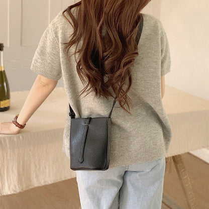 Side profile showing the structured shape of the black lychee leather bag.