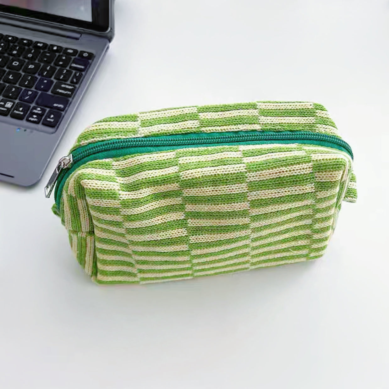 Front view of green striped knitted makeup bag, easy to pack for trips and daily use.